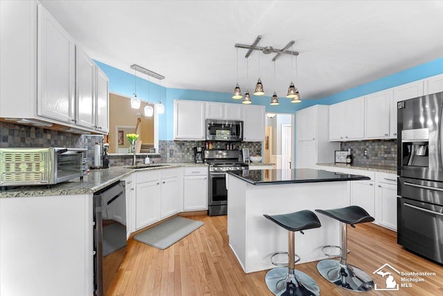 25345 Hunter Ln, Flat Rock, MI 48134 - kitchen featuring appliances with stainless steel finishes, tasteful backsplash, a center island, white cabinetry, and a sink