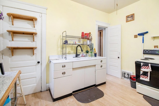 kitchen featuring white range with electric stovetop, a sink, light wood-type flooring, light countertops, and white cabinets