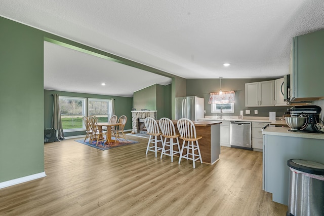 3311 5 Mile Rd, Sears, MI 49679 - kitchen with stainless steel appliances, light countertops, a kitchen bar, a center island, and light wood-style flooring
