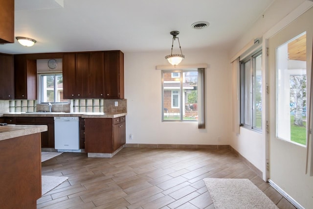 12225 SW Torch Lake Dr SW, Rapid City, MI 49676 - kitchen with white dishwasher, light countertops, backsplash, a sink, and hanging light fixtures
