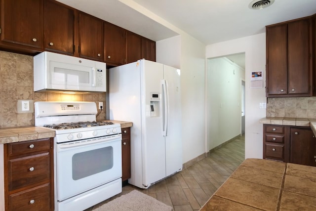 12225 SW Torch Lake Dr SW, Rapid City, MI 49676 - kitchen featuring white appliances, backsplash, dark brown cabinets, wood finished floors, and baseboards