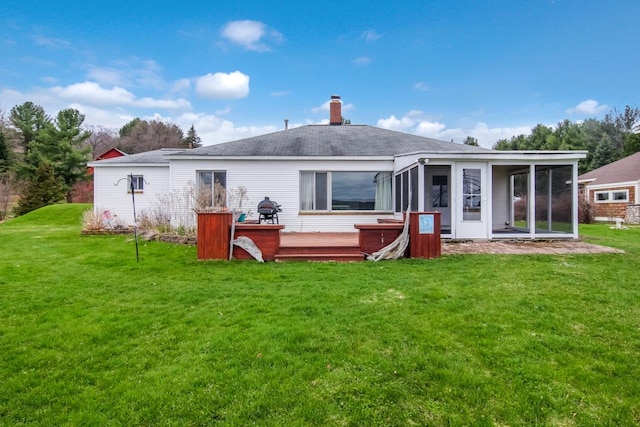 12225 SW Torch Lake Dr SW, Rapid City, MI 49676 - back of house featuring a sunroom, a deck, a chimney, and a lawn