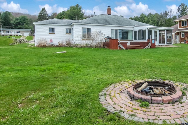 12225 SW Torch Lake Dr SW, Rapid City, MI 49676 - back of property with a fire pit, a sunroom, a yard, a chimney, and a shingled roof
