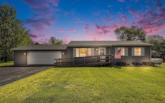 ranch-style house with a garage, asphalt driveway, and a front lawn