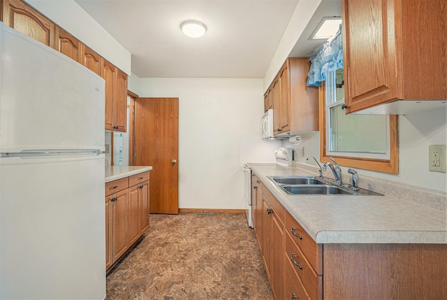 kitchen featuring white appliances, a sink, light countertops, brown cabinets, and baseboards