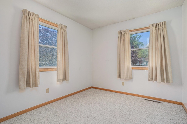 unfurnished room featuring healthy amount of natural light, carpet floors, and baseboards