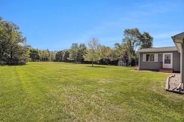 view of green lawn with entry steps, a storage unit, and an outdoor structure