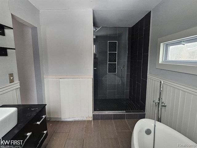 7415 Linden Rd, Fenton, MI 48430 - bathroom featuring a wainscoted wall, wood finished floors, a freestanding tub, a stall shower, and vanity