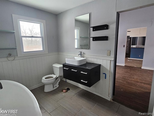 7415 Linden Rd, Fenton, MI 48430 - bathroom with wainscoting, a freestanding tub, toilet, vanity, and wood finished floors