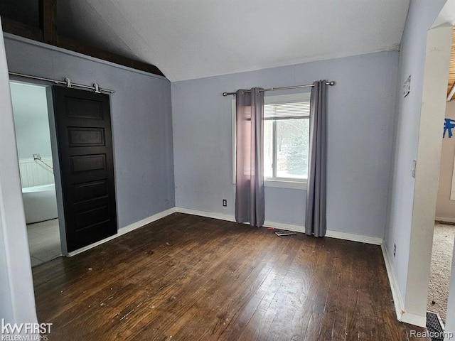 7415 Linden Rd, Fenton, MI 48430 - spare room with vaulted ceiling, hardwood / wood-style flooring, a barn door, and baseboards