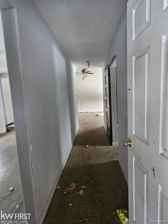 7415 Linden Rd, Fenton, MI 48430 - hallway featuring a barn door, a textured ceiling, and baseboards