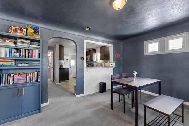 dining area with arched walkways and light carpet