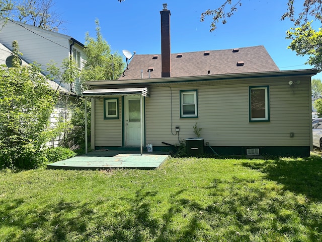 rear view of house featuring a yard, central AC unit, and a shingled roof