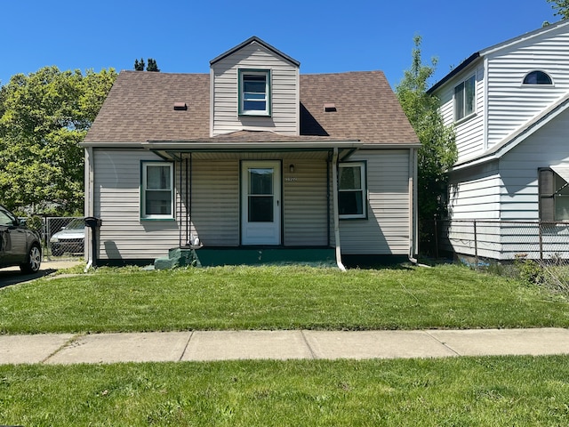 view of front of house with a front lawn, roof with shingles, and covered porch