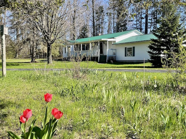ranch-style house featuring a porch, metal roof, and a front yard