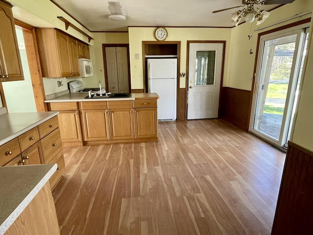 kitchen featuring white appliances, a sink, light wood finished floors, a wainscoted wall, and ceiling fan