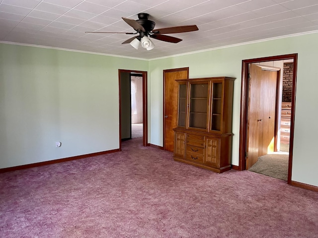 unfurnished bedroom with carpet flooring, ornamental molding, baseboards, and ceiling fan