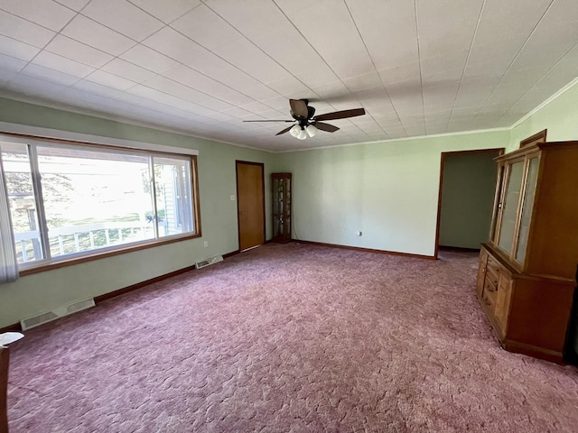 carpeted empty room with ceiling fan, baseboards, and ornamental molding