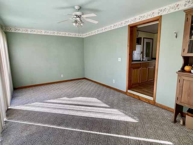 carpeted empty room featuring ceiling fan and baseboards