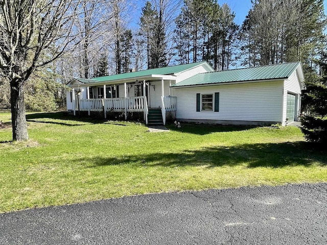 view of front facade featuring covered porch, a garage, a front yard, and metal roof