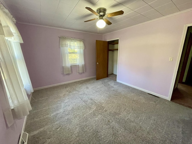 unfurnished bedroom featuring crown molding, carpet, a closet, baseboards, and a ceiling fan