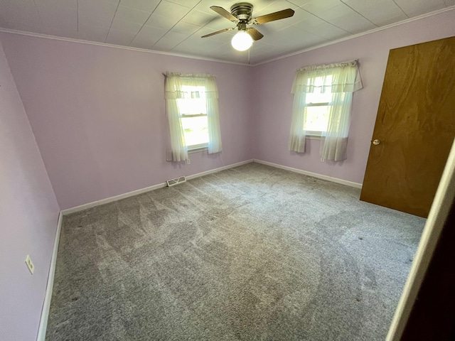 empty room featuring ornamental molding, a ceiling fan, carpet floors, and baseboards
