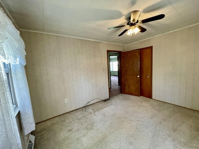 carpeted spare room featuring a ceiling fan and crown molding