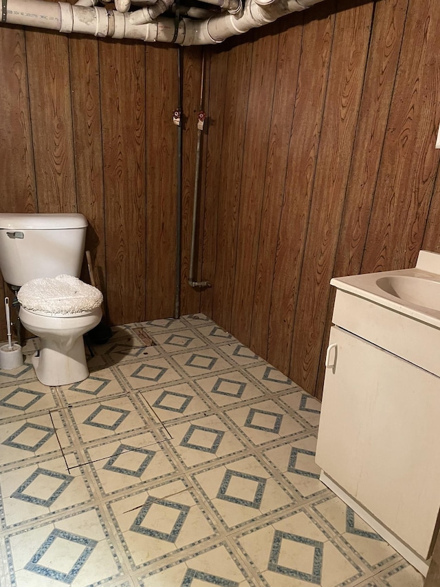 bathroom featuring wood walls, toilet, and vanity