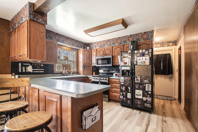 50427 M 51 N, Dowagiac, MI 49047 - kitchen featuring appliances with stainless steel finishes, a peninsula, light wood-type flooring, brown cabinets, and tasteful backsplash