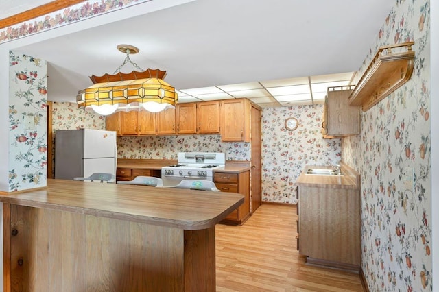 8439 Shoshoni Pass, Pigeon, MI 48755 - kitchen featuring wallpapered walls, white appliances, light wood finished floors, a sink, and a peninsula