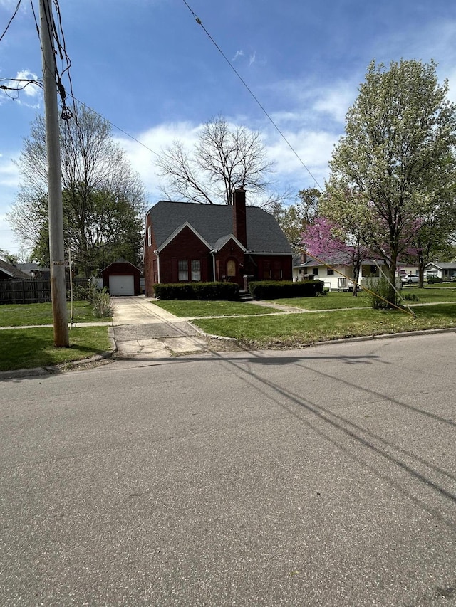 view of front of house featuring concrete driveway, a detached garage, a front yard, and an outdoor structure