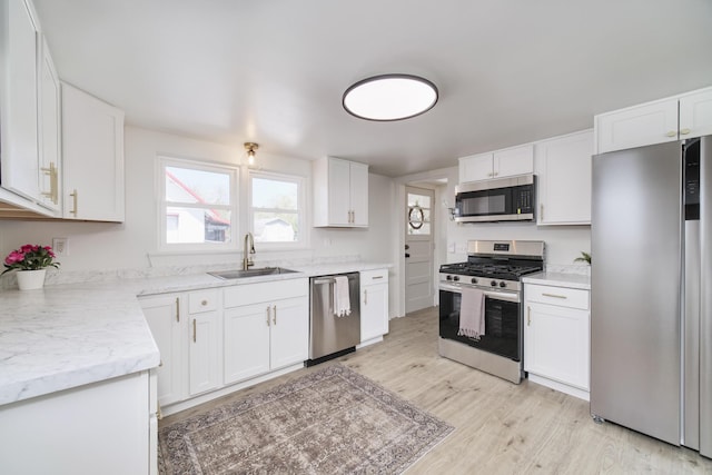 923 Maple St, Ludington, MI 49431 - kitchen with appliances with stainless steel finishes, a sink, light wood-style floors, white cabinets, and light stone countertops