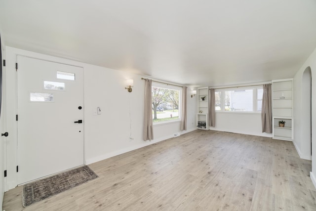 923 Maple St, Ludington, MI 49431 - foyer entrance with light wood-style floors, baseboards, and arched walkways