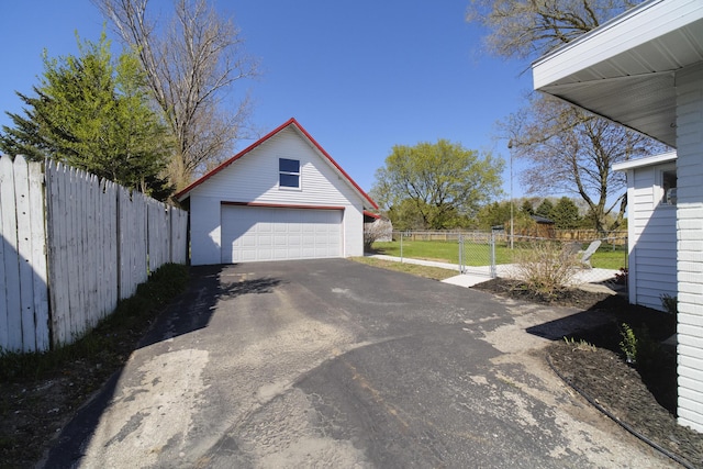923 Maple St, Ludington, MI 49431 - view of property exterior featuring an outdoor structure, a garage, fence, and driveway