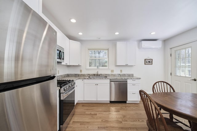 2073 Gunn Rd, Manistee, MI 49660 - kitchen featuring appliances with stainless steel finishes, a sink, light stone countertops, recessed lighting, and a wall mounted air conditioner