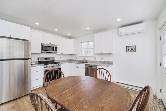 2073 Gunn Rd, Manistee, MI 49660 - kitchen featuring appliances with stainless steel finishes, a baseboard radiator, a wall mounted air conditioner, a sink, and light wood-style floors