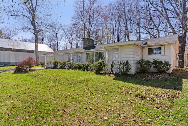 back of house featuring a lawn and a chimney