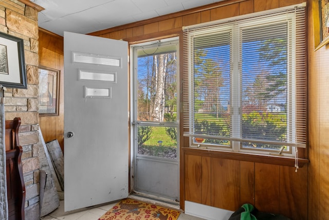 doorway to outside featuring wooden walls and healthy amount of natural light