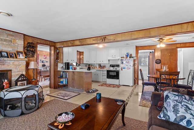 living area with wooden walls, ceiling fan, light tile patterned floors, and a fireplace