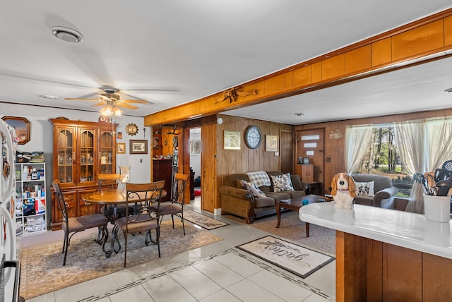living area with a ceiling fan and wood walls