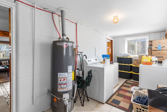 laundry room with gas water heater, washer and clothes dryer, concrete block wall, and light tile patterned floors