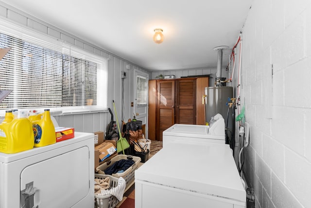 clothes washing area featuring washer and dryer, gas water heater, and concrete block wall