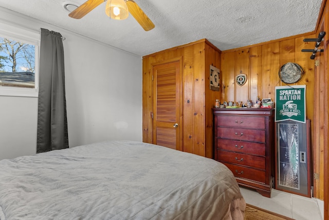 bedroom with wood walls, a closet, a textured ceiling, and ceiling fan