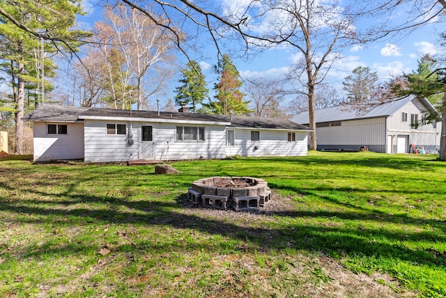 rear view of house with an outdoor fire pit and a lawn
