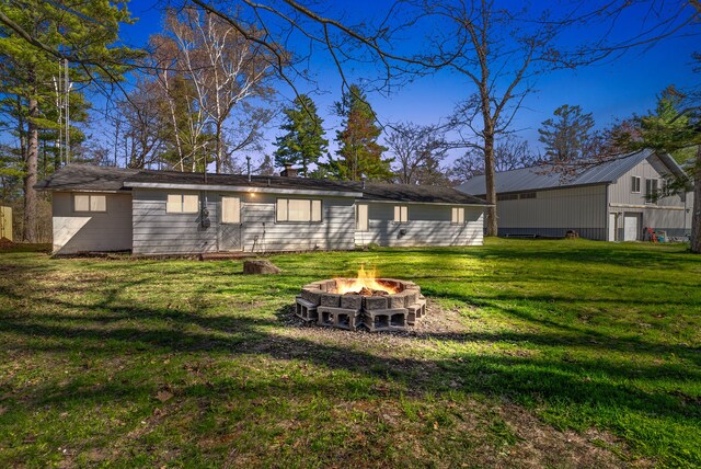 back of house featuring a fire pit and a lawn