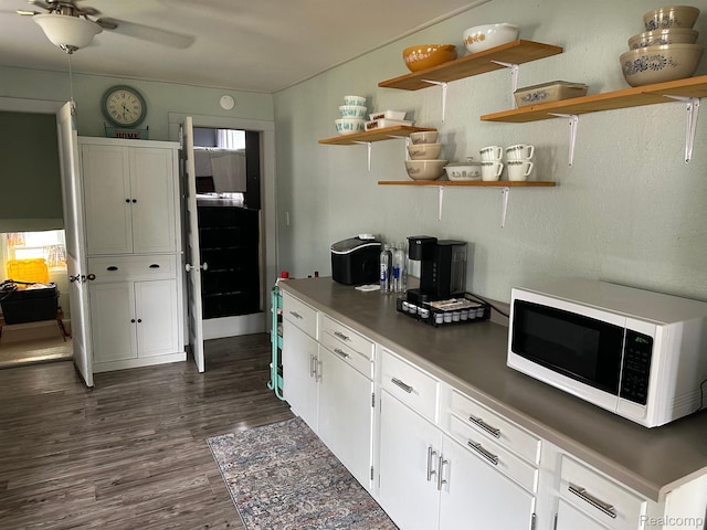 7980 W Gilford Rd, Reese, MI 48757 - kitchen with white microwave, dark wood-style flooring, open shelves, and white cabinets