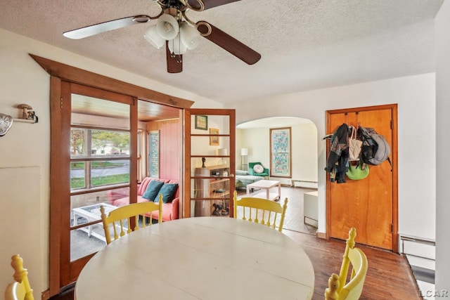 126 Litchfield St, Clinton, MI 49236 - dining space featuring a textured ceiling, arched walkways, wood finished floors, baseboard heating, and a ceiling fan