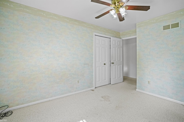 unfurnished bedroom with carpet flooring, baseboards, a closet, a ceiling fan, and wallpapered walls