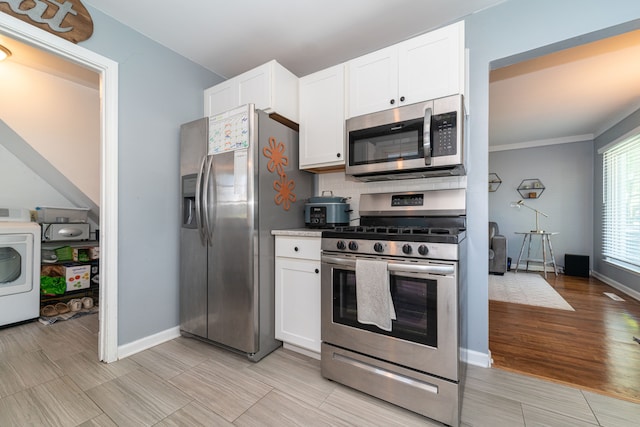 kitchen featuring stainless steel appliances, washer / clothes dryer, white cabinets, and baseboards