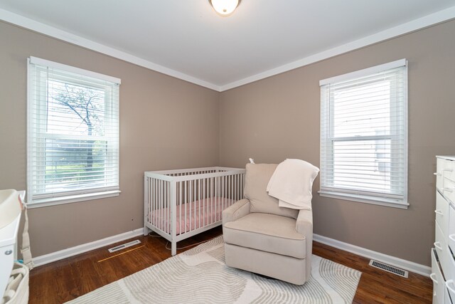 bedroom with wood finished floors, baseboards, and a crib